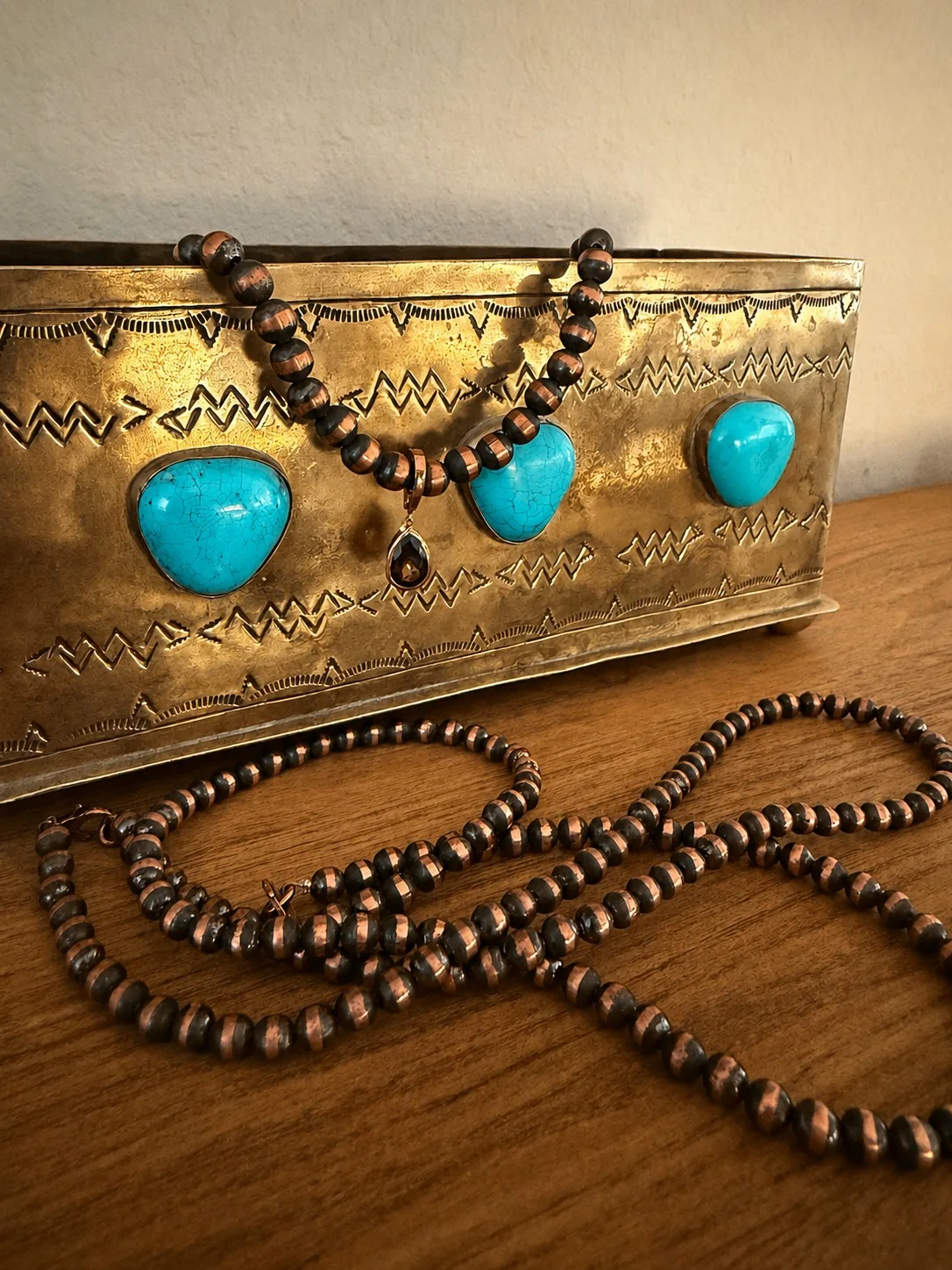 Jewelry displayed on a decorative metal box with turquoise accents